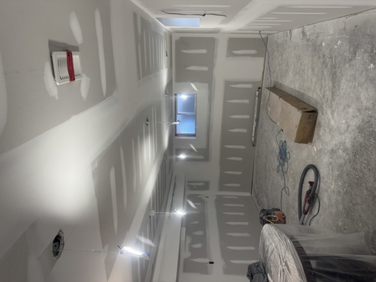 The same basement room taped and coated, ceiling sanded smooth and ready for paint